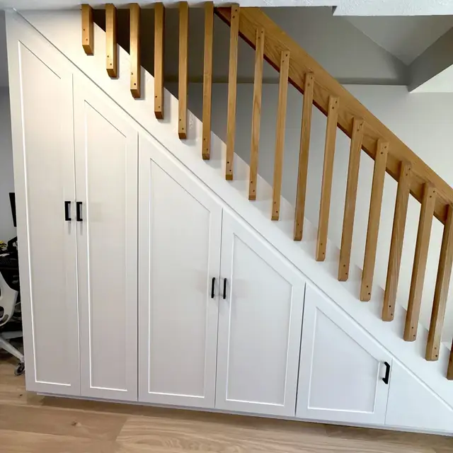 White under-stair storage cabinets built into a staircase in Brookline, MA